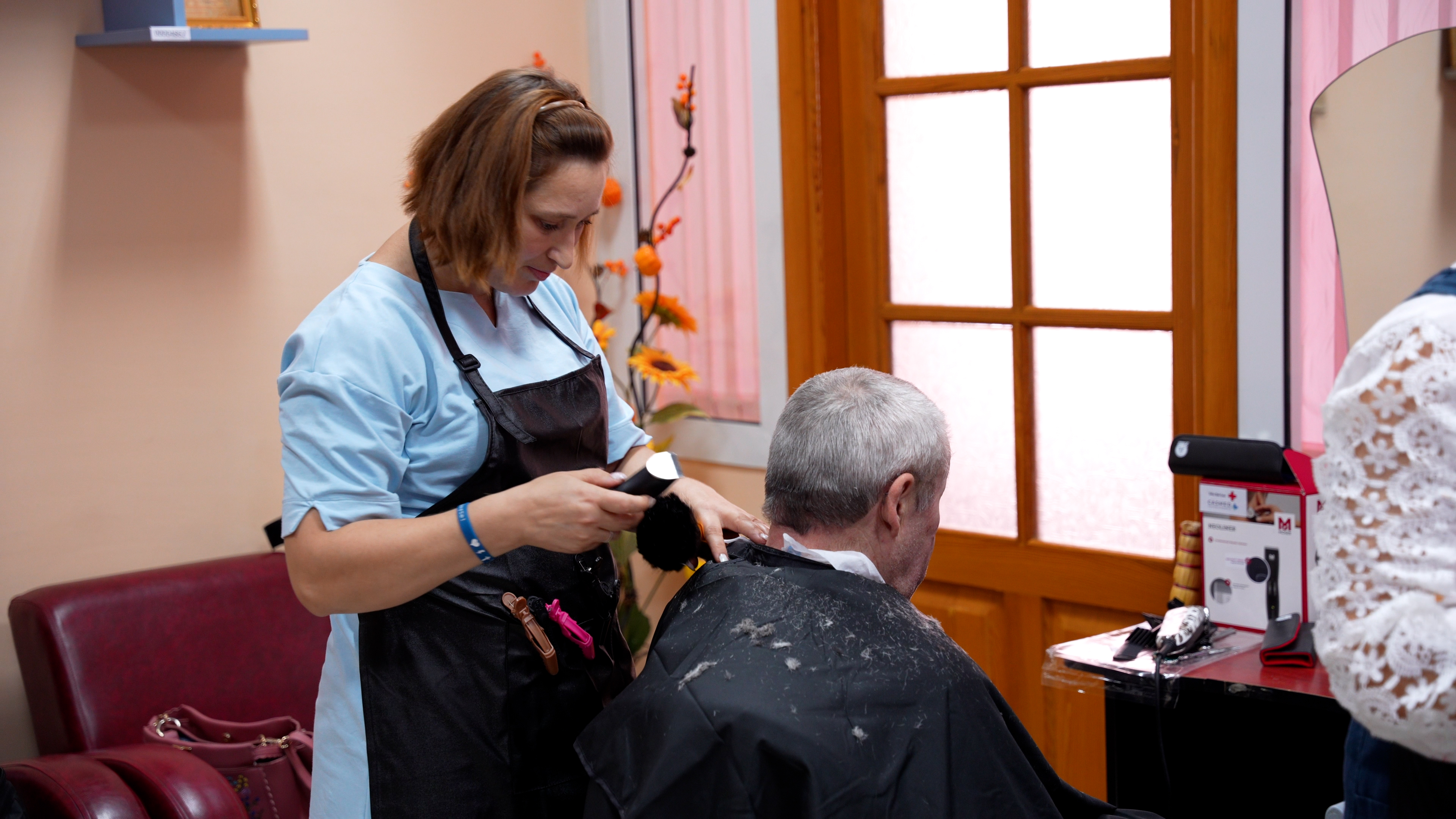mulher cortando cabelo de um senhor